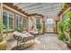 Cozy outdoor patio with comfortable seating, brick flooring, pergola, and lush greenery at 10408 Mezzanino Ct, Las Vegas, NV 89135