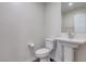 This powder room features a pedestal sink, white fixtures and wood grain flooring at 10777 Briset Ct, Las Vegas, NV 89166