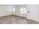 Bright living room with wood-look flooring, white walls, and natural light from large windows at 10777 Briset Ct, Las Vegas, NV 89166