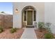 Inviting front entrance with an arched doorway, desert landscaping, a warm lantern and a secure front door at 11132 Ferragamo Ct, Las Vegas, NV 89141