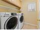 Convenient laundry room featuring a front loading washer and dryer with cabinets and shelving for storage at 11132 Ferragamo Ct, Las Vegas, NV 89141