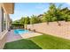 Private backyard featuring a sparkling pool, artificial grass, and a charming brick wall at 12048 Portamento Ct, Las Vegas, NV 89138