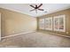 Bright bedroom featuring a ceiling fan, carpeted floors, and three large windows for ample natural light at 1561 Campfire Ln, Mesquite, NV 89034