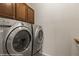 The laundry room has a silver Whirlpool washer and dryer with dark wood cabinets above at 1561 Campfire Ln, Mesquite, NV 89034
