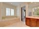Bright bathroom features a soaking tub, tile flooring, a double sink vanity and a window with plantation shutters at 17 Stonemark Dr, Henderson, NV 89052