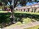 Exterior view of the townhome complex with a green lawn, sidewalk, and mature trees at 2524 Charleville Ave # 102, Las Vegas, NV 89106