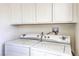 Close-up of a white washer and dryer with white cabinets above in the laundry area at 2825 Berg St, North Las Vegas, NV 89030