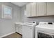 Functional laundry room with white washer, dryer, sink, and ample cabinet space at 305 Rezzo St, Las Vegas, NV 89138