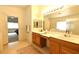 Bright bathroom with double sinks, wood cabinetry, and a doorway to another room at 343 Dune Ridge Ave, North Las Vegas, NV 89031