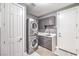 Convenient laundry room featuring stacked washer and dryer units, custom cabinets, and ample counter space at 3552 Coventry Gardens Dr, Las Vegas, NV 89135