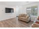 Bright living room with wood floors, a large window, and a modern TV at 3585 Arcadian Sea St, Las Vegas, NV 89106
