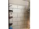 White tiled shower area with shower head fixture and convenient mounted shelving for storage at 400 National St, Henderson, NV 89015