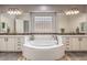 Elegant bathroom with a soaking tub, dual vanities, and a unique glass block window for natural light at 409 Lake Windemere St, Las Vegas, NV 89138