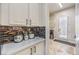 Hallway with white cabinets, a mosaic backsplash, and a view to the exterior door at 409 Lake Windemere St, Las Vegas, NV 89138