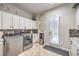 Well-organized laundry room featuring stainless steel washer/dryer, white cabinets, and stylish backsplash at 409 Lake Windemere St, Las Vegas, NV 89138