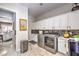 Functional laundry area boasts stainless steel appliances, bright white cabinets, and decorative backsplash at 409 Lake Windemere St, Las Vegas, NV 89138