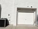 Attached one-car garage with white door and modern black air conditioning unit sitting on the concrete slab at 5024 Starfinder Ave, Las Vegas, NV 89108