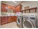 Well-organized laundry room featuring wood cabinets, a sink, and modern washer and dryer units at 5701 Mary Lou St, Pahrump, NV 89061