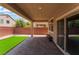 Comfortable covered patio with brick flooring, small patch of turf, and a dark wood bench, perfect for outdoor living at 6412 Dimatteo St, Las Vegas, NV 89148