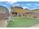Inviting backyard featuring an artificial grass area, shade sail, swingset and covered patio at 7122 Red Gulch St, North Las Vegas, NV 89084