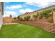 The backyard features artificial turf, a brick retaining wall, and a partially shaded area at 8257 Skye Peak St, Las Vegas, NV 89166