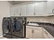 Well-organized laundry room with washer, dryer, utility sink, dark countertop, and white storage cabinets at 8257 Skye Peak St, Las Vegas, NV 89166