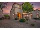 Two story home with a two car garage, neutral paint, rock accents and manicured landscaping at dusk in Las Vegas, Nevada at 8647 Tortoise Canyon Ct, Las Vegas, NV 89148