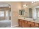 Bathroom featuring double sinks, a large mirror, and an archway entrance to bedroom area at 8664 Frasure Falls Ave, Las Vegas, NV 89178