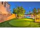 Lush backyard showcasing a putting green and a stunning rock waterfall feature with ambient lighting at 9805 Turtle Walk Ave, Las Vegas, NV 89149