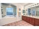 Bright bathroom featuring double vanity sinks, updated fixtures, and soaker tub with window at 9805 Turtle Walk Ave, Las Vegas, NV 89149
