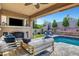Outdoor living space with a built-in fireplace, TV, and seating area by the pool at , Las Vegas, NV 89138