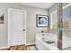 Bathroom featuring a bathtub with glass shower doors, decorative picture and wood-look flooring at 10426 Mount Washington Ave, Las Vegas, NV 89166