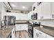 Well-lit kitchen with stainless steel appliances, granite countertops and white cabinets and light-colored floor at 10426 Mount Washington Ave, Las Vegas, NV 89166