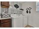 Functional laundry room with washer, dryer, cabinets, shelves, and stylish wallpaper at 10426 Mount Washington Ave, Las Vegas, NV 89166
