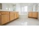 Bright bathroom featuring a jacuzzi bathtub, white tile floors, and wooden cabinets with double sinks at 1100 Cypress Ridge Ln, Las Vegas, NV 89144