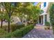 Charming front yard with lush greenery, a paved walkway, and an outdoor dining area at 12056 Royal Dolnoch Ct, Las Vegas, NV 89141