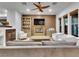 Cozy living room with a fireplace, built-in bookshelves, and comfortable seating with a ceiling fan at 12056 Royal Dolnoch Ct, Las Vegas, NV 89141