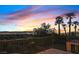 A balcony view of a vibrant sunset over the city skyline, complemented by palm trees and wrought iron railings at 1221 Diamond Valley St, Henderson, NV 89052
