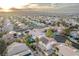 Expansive aerial view captures a neighborhood with well-maintained homes and the city skyline in the distance at sunset at 1287 Dove Tree Ct, Henderson, NV 89014