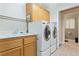 Functional laundry room with a sink, countertop, upper cabinets, and modern washer and dryer at 1287 Dove Tree Ct, Henderson, NV 89014