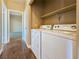Convenient laundry area with modern white washer and dryer, and upper shelving at 1851 Hillpointe Rd # 2124, Henderson, NV 89074