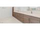 Modern bathroom with dual sink vanity, wood-grain cabinets, white countertop, and decorative tile flooring at 2588 Mizzoni Cir, Henderson, NV 89052