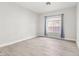 Bright bedroom with a window featuring neutral walls, wood-look tile flooring, and privacy enhancing curtains at 2588 Mizzoni Cir, Henderson, NV 89052