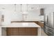 Well-lit kitchen with an island, stainless steel refrigerator, and contemporary design elements at 2588 Mizzoni Cir, Henderson, NV 89052