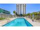 Community pool with sun loungers, secure fencing, greenery, and clear blue sky at 3930 University Center Dr # 311, Las Vegas, NV 89119