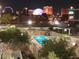 Night aerial view of a community pool with city skyline in the background at 3930 University Center Dr # 312, Las Vegas, NV 89119