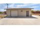 A detached garage featuring a white garage door, beige stucco siding and concrete driveway is set against a blue sky at 4691 Sun Valley Cir, Las Vegas, NV 89122