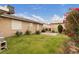 Wide view of the fenced backyard showing lush grass and mature flowering shrubs at 4998 Rappahanock St, Las Vegas, NV 89122