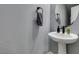 Stylish powder room featuring a pedestal sink with modern faucet and a round mirror at 649 Tranquil Jade St, Las Vegas, NV 89138