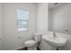 Well-lit powder room featuring a modern pedestal sink and toilet under a window at 6772 Violet Cascade Ave, Las Vegas, NV 89156